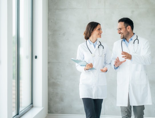 Zwei Ärzte beraten sich auf dem Gang während dem Gehen